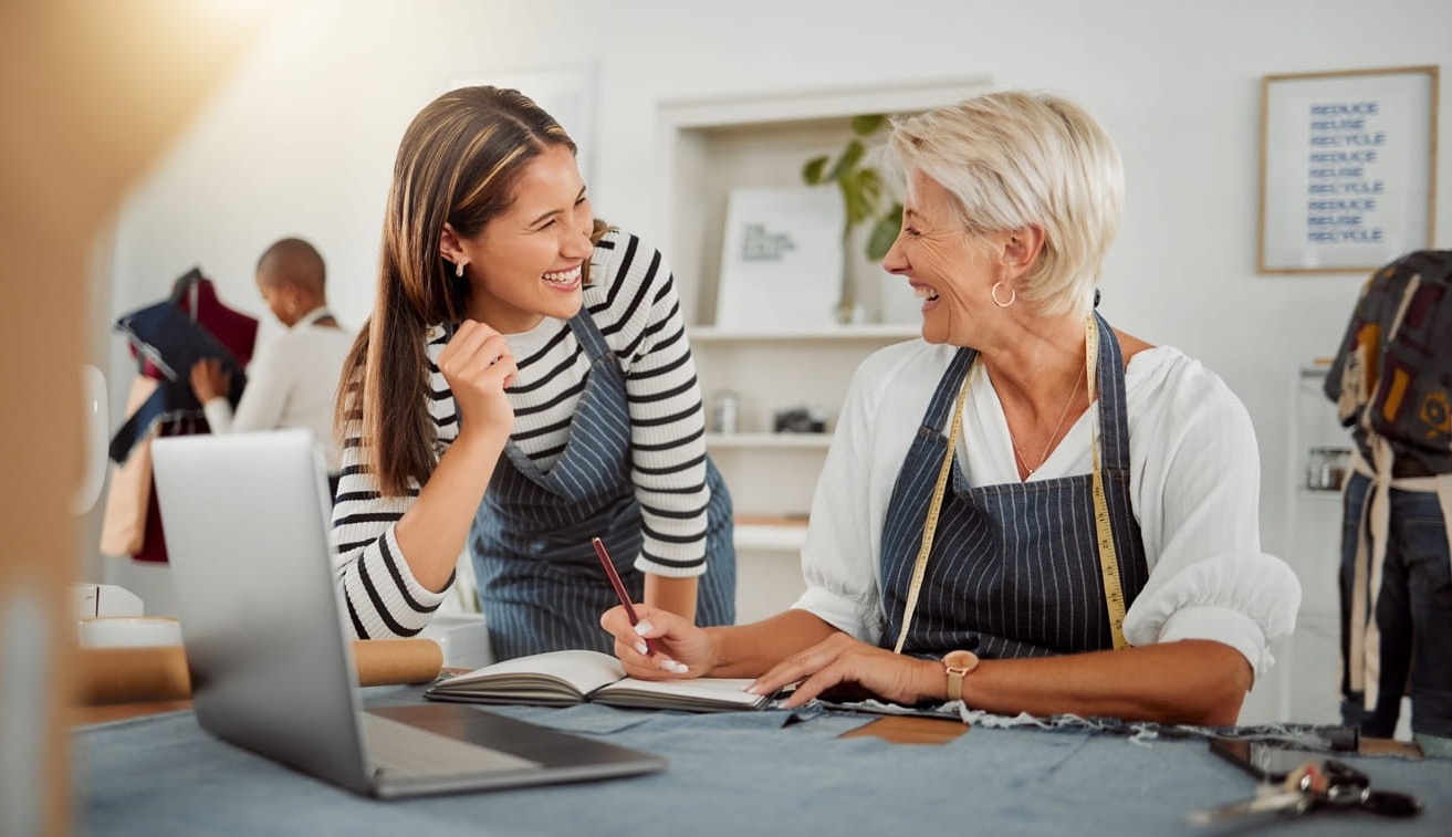 two clothing designers using laptop while working with material